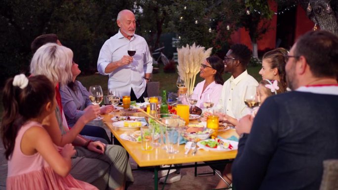 一位老人在与他的多种族家庭共进晚餐时敬酒