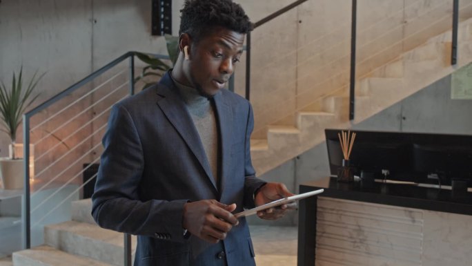 年轻的黑人拿着平板电脑在大厅里进行生动的工作对话
