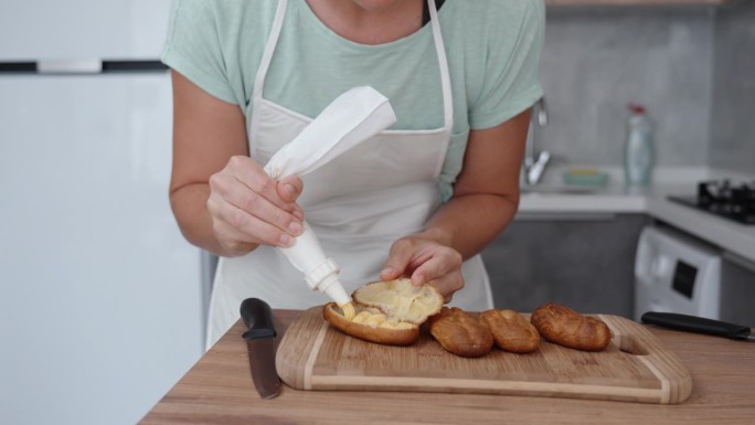 这个女人用慢动作把奶油从糕点袋里挤到泡芙上。
