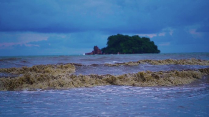 大海里的大浪打在沙滩上，海水浑浊。