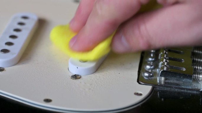 一名男子正在清洗装有白色拾音器的黑色电吉他。吉他服务理念。4k视频片段UHD 3840x2160