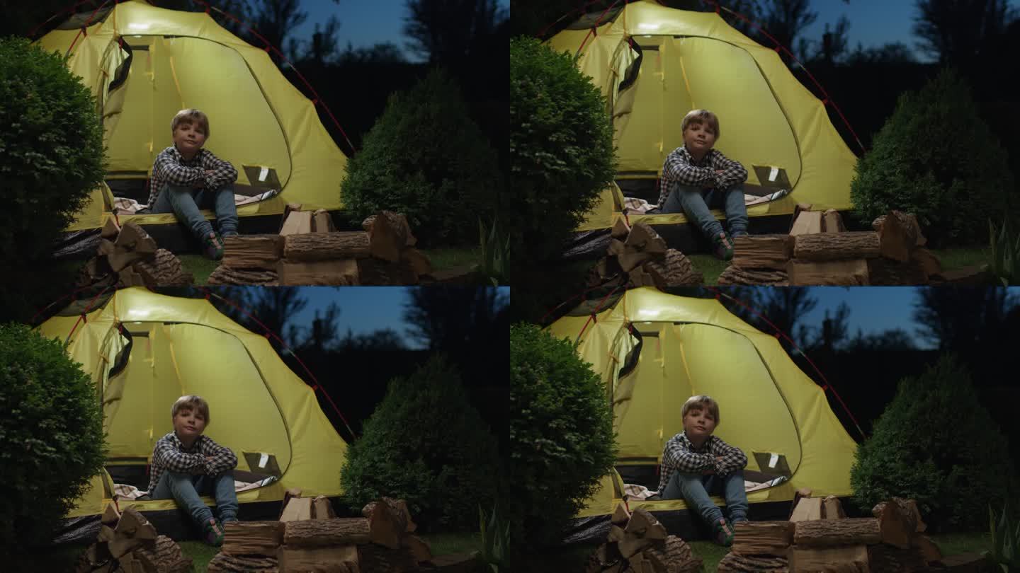 男孩坐在帐篷外面。