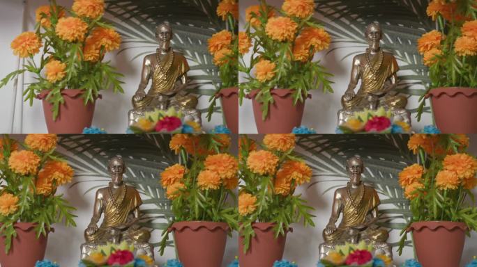 架子上的佛像在橙色的花朵之间