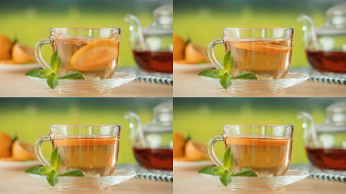 杯中的柑橘茶特写。将橙子放入薄荷茶中，健康的早晨，排毒的热草药饮料。