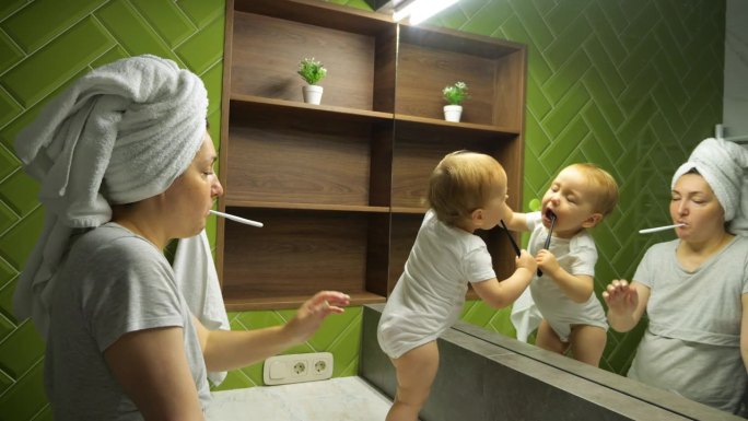 女人和小孩看着大镜子刷牙
