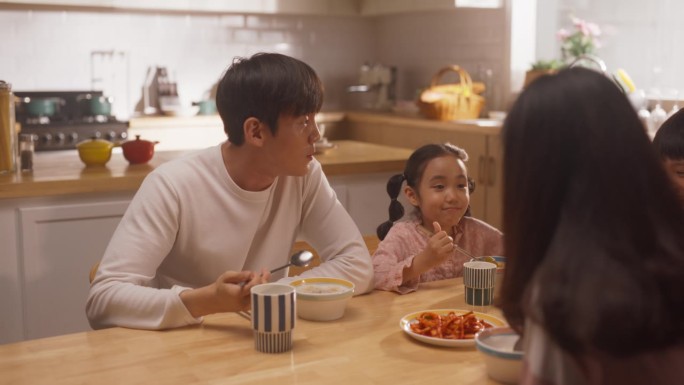 穿着睡衣一起吃早餐或午餐的韩国家庭肖像。年轻的父母和他们可爱可爱的孩子吃一顿营养健康的饭，开始充满活