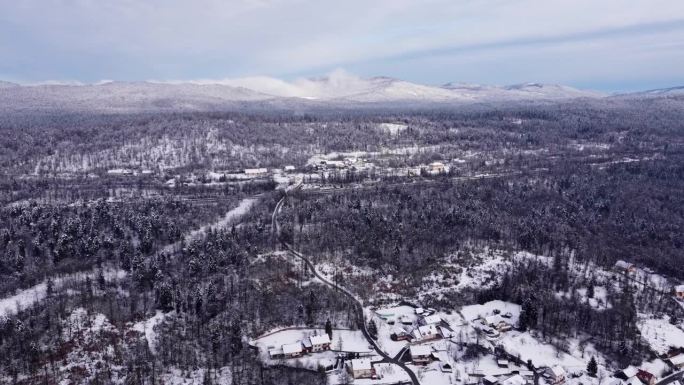 斯洛文尼亚无人机拍摄的冬季森林中白雪覆盖的乡村地区、村庄和道路的惊人景象。