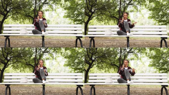 一个微笑的年轻卷发女子坐在秋天公园的长椅上，用手机聊天。