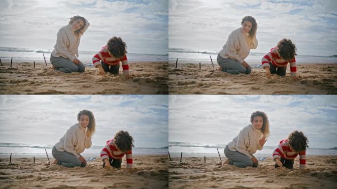 年轻的妈妈和可爱的男孩在沙滩上玩耍。幸福的一家人一起堆沙堡。