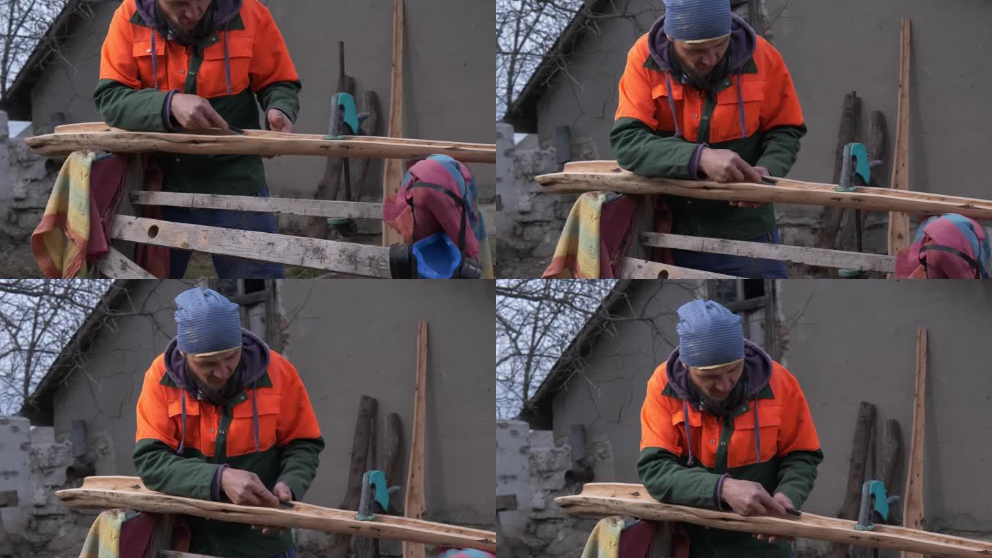 一名穿着工作服的成年白人男子小心翼翼地将一根圆木的核心剪掉，作为一种带有树桩的工具。手工工作。澳大利
