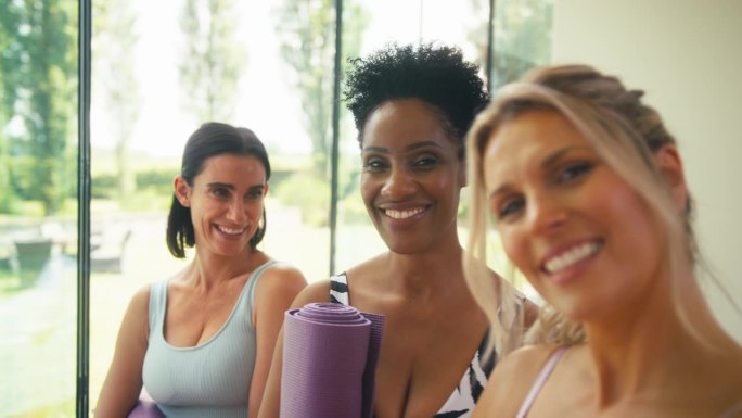 三个成熟的女性朋友穿着健身服在健身房或瑜伽课上自拍的POV镜头