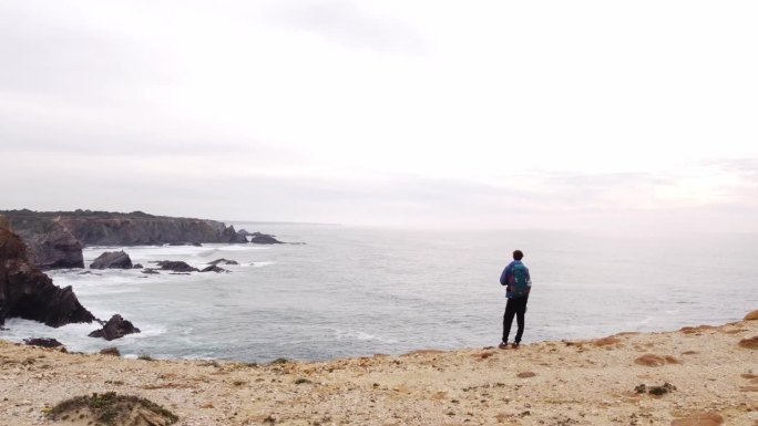 一名男子站在悬崖边上眺望葡萄牙西海岸。一个思考和了解大西洋力量的地方。4k视频