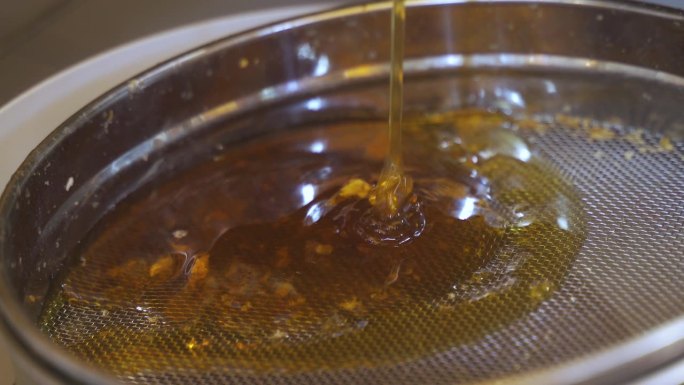 蜂蜜从蜂蜜提取器流出，流到滤网上。