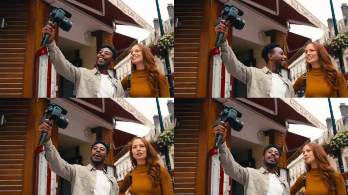 年轻夫妇一起旅行通过城市视频记录到手持三脚架摄像机