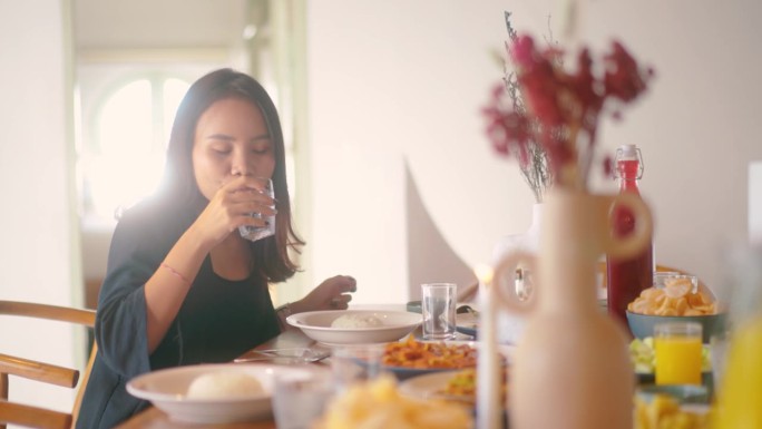 美丽的亚洲女人享受饭菜精心装饰的餐桌