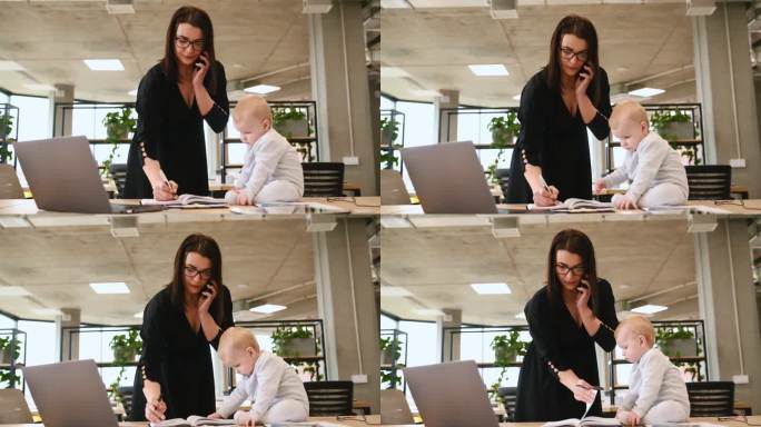 妈妈在办公室工作，她的小儿子坐在桌子上。