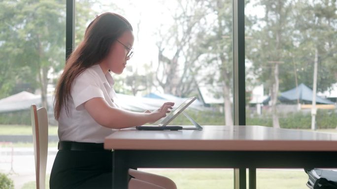 亚洲年轻学生在图书馆用平板电脑做笔记
