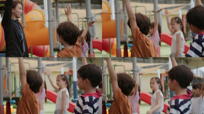 在一个阳光明媚的夏日，一大群孩子——男孩和女孩——站在一起，举起双手，脸上挂着快乐的表情。