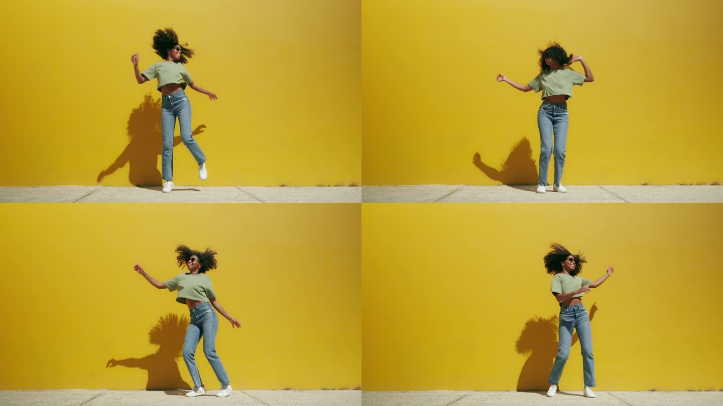 年轻快乐的非裔美国妇女跳到室外的黄色墙壁上。