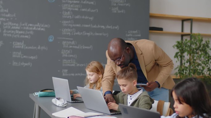 非裔美国教师帮助学生使用笔记本电脑