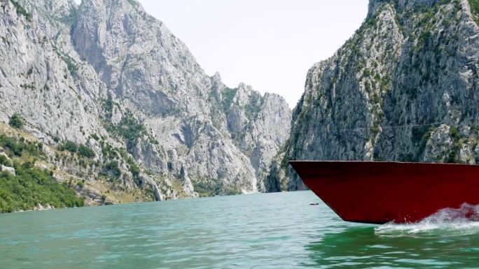 阿尔巴尼亚，科曼湖，湖面上一艘红船的船头，背景是被诅咒的山脉