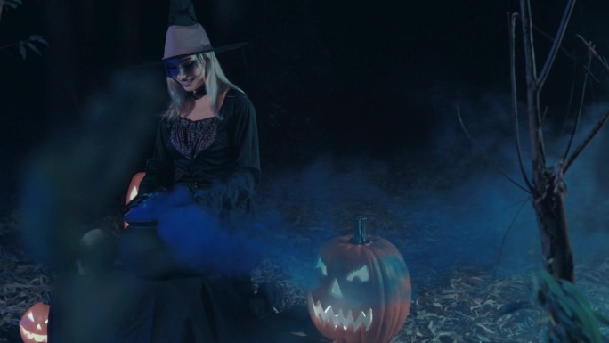 戴着帽子和斗篷的神秘女巫师在她的坩埚里施咒，为万圣节做准备