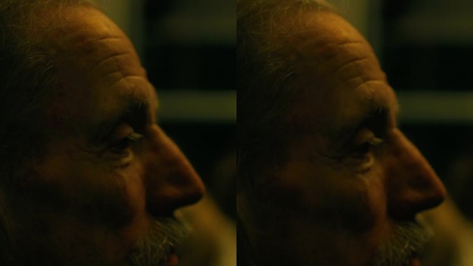 垂直视频，在夜间乘坐火车的沉思老人的特写肖像，通过双层玻璃观看