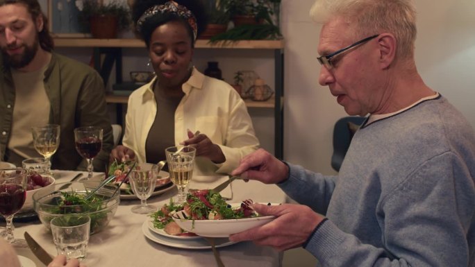 和家人一起吃饭时，男人把沙拉放在盘子里