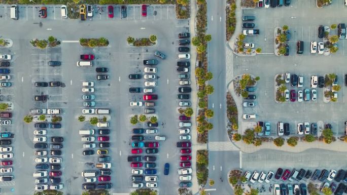 鸟瞰图，许多五颜六色的汽车停在停车场，有线条和标记的停车位和方向。佛罗里达州萨拉索塔市西斯塔基海滩前