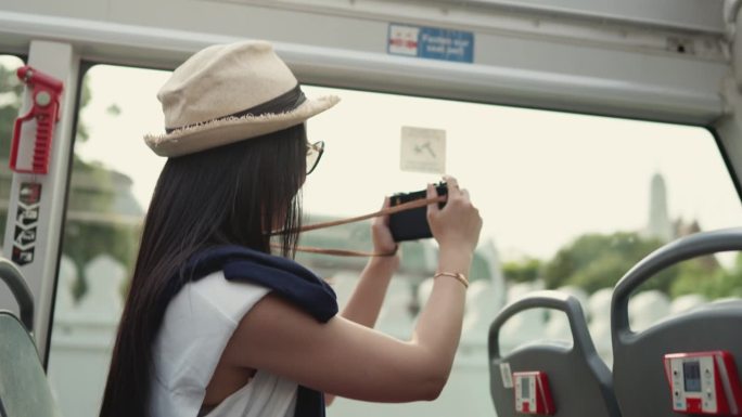 美丽的女人用相机捕捉城市旅游巴士上的景色