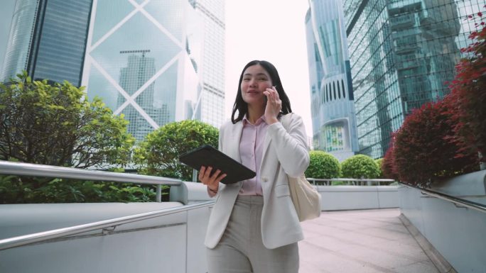 走在香港商业中心中心的女商人用你的手机来协调工作。