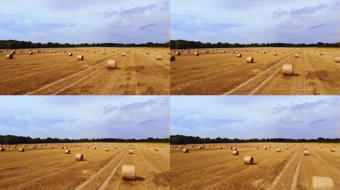 在一个美丽的夏日，无人机在田野里的稻草捆上飞行