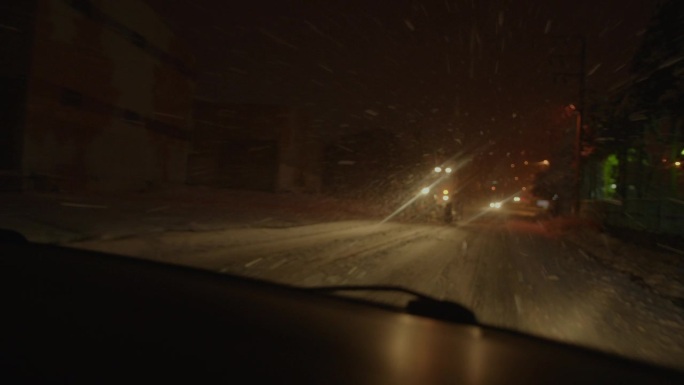 神奇的冬季之旅:夜间汽车前窗镜头反映雪景，模糊的抽象灯光和喜怒无常的气氛