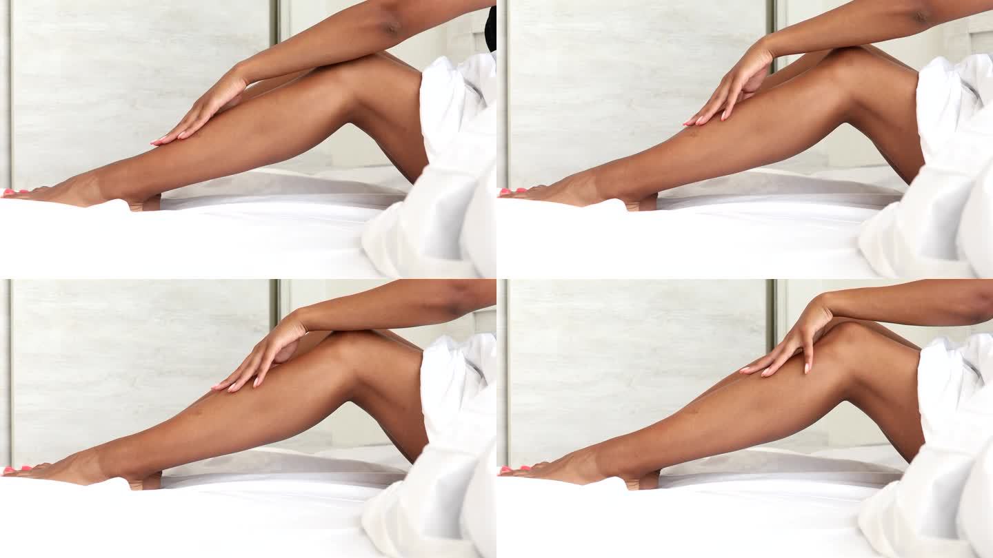 在床上脱毛后，美丽的黑人女性拥有完美健康柔滑的腿部皮肤。