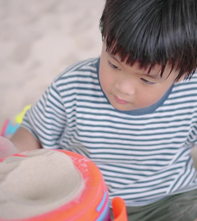 一个小男孩独自在沙坑里玩玩具。