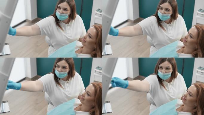 在牙医对显示器上的全景图像进行x光和断层扫描分析的过程中，患者接受专业的牙齿治疗和护理建议