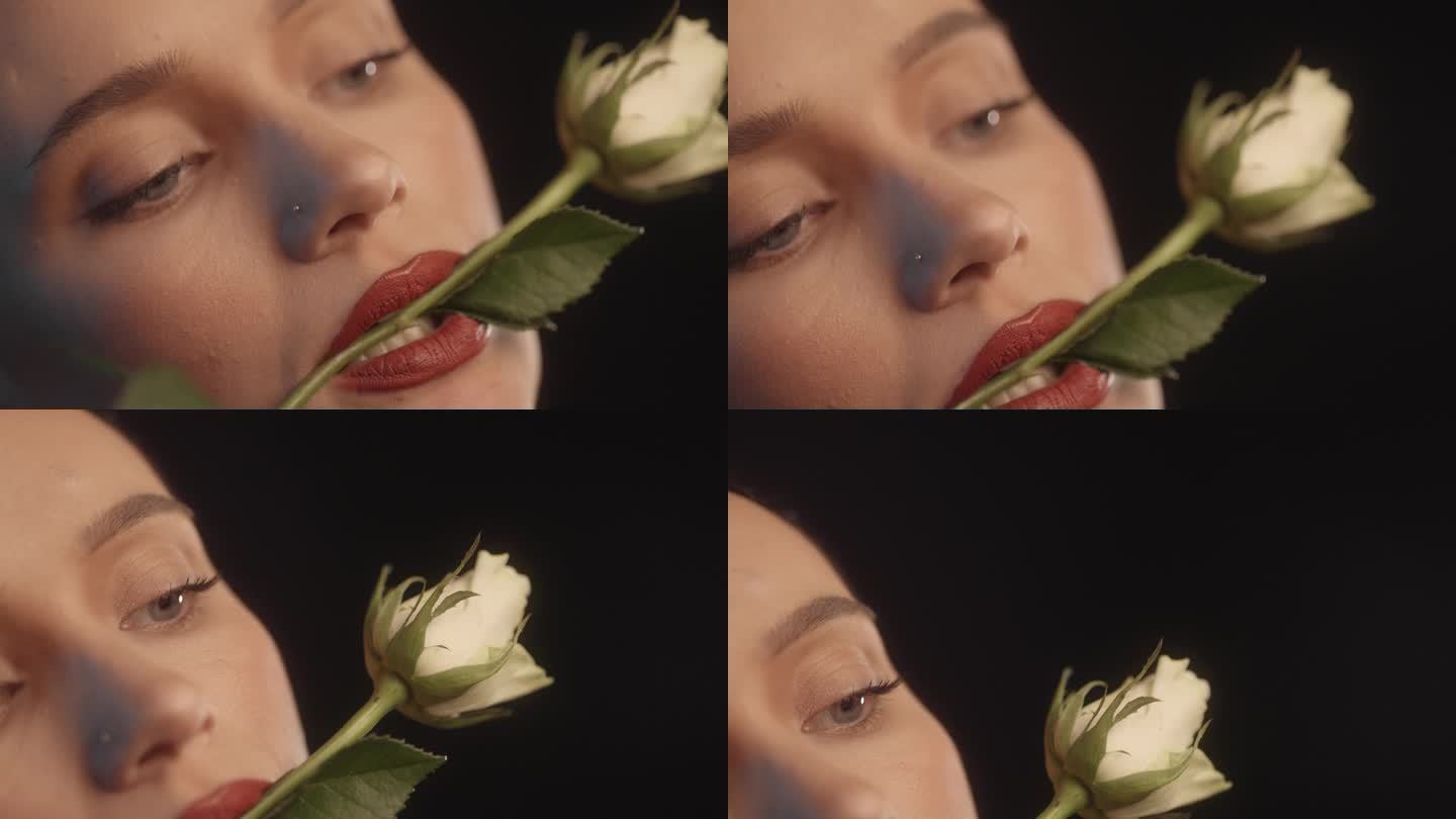 美丽性感的女人用红色的口红黑色的背景工作室拍摄的姿势与一个白玫瑰在她的嘴里