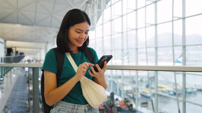 玩手机通讯，在候机楼内等候登机的女子旅行。