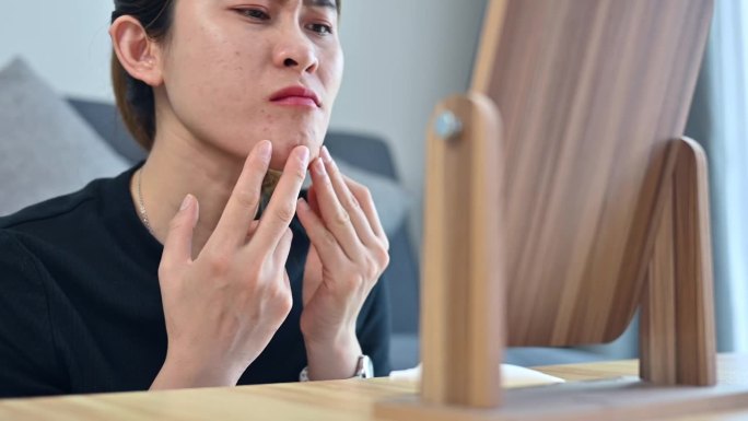 亚洲女性在看到脸上出现粉刺和皱纹时担心自己的脸。