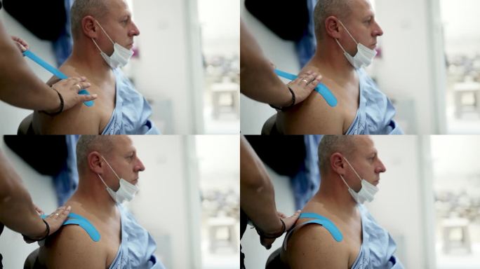 男性治疗师应用运动机能胶带治疗男性运动员肩部损伤。创伤后康复，运动物理治疗