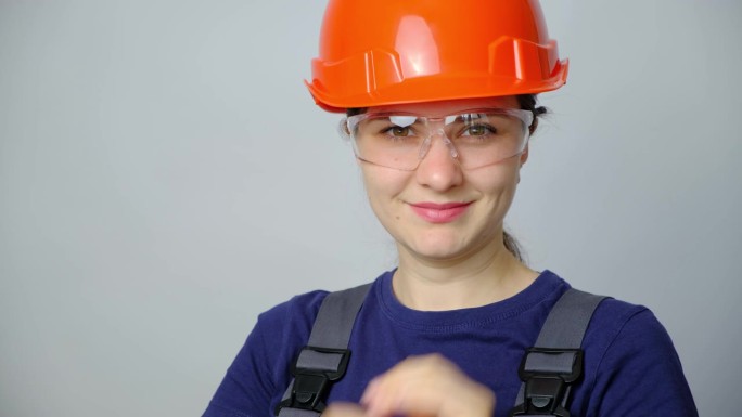 一名身穿工作服、头戴头盔的女工程师戴着白色背景的护目镜。