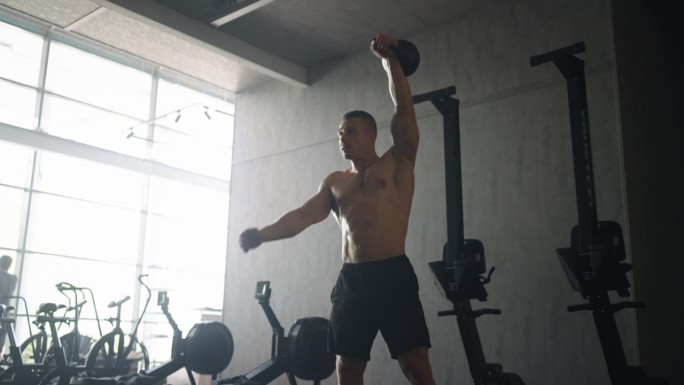 运动员在健身房训练，举壶铃和训练他的身体，裸露的躯干与救济肌肉
