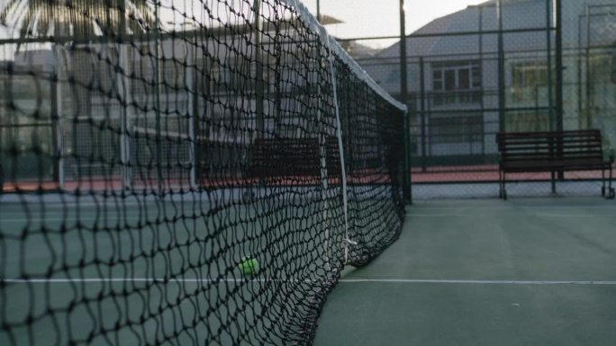 年轻的混血儿男子在运动场上练习网球时拿起网子