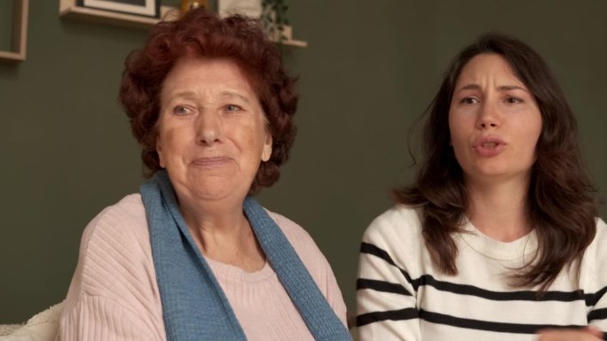 奶奶和孙女坐在公寓的沙发上，看着足球比赛，为自己的球队的失败感到失望