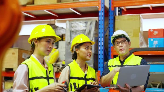一群亚洲男女工程师在建筑工地使用机械臂一起工作。