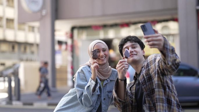 亚洲年轻人喜欢在街上用智能手机吃冰淇淋并把它发布到社交媒体上