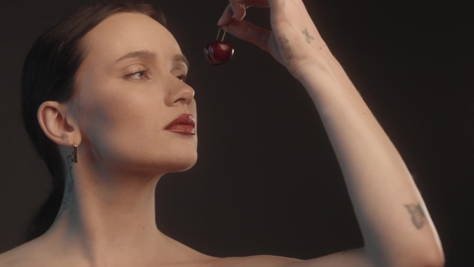 美丽感性的女人与红色口红黑色背景工作室拍摄摆樱果耳环