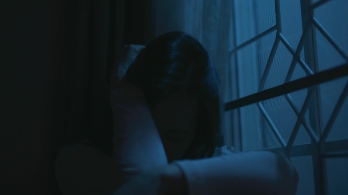 忧郁的少女晚上坐在窗边