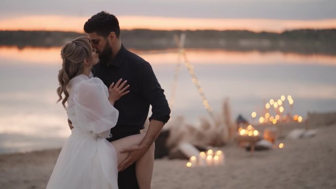 帅哥在沙滩上拥抱和亲吻他的性女友，浪漫的婚礼情侣