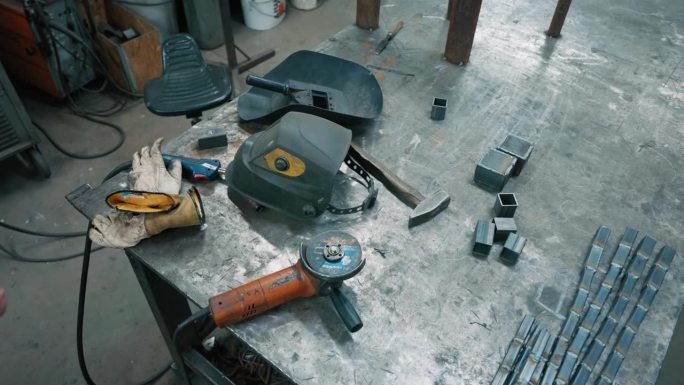 照明工厂工作台上金属件附近的SLO MO焊接头盔和工具